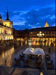 een groep tafels met parasols in een stad 's nachts bij Arquitecto de la Vida - Plaza Mayor in León