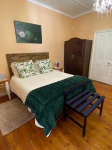 a bedroom with a bed with a green blanket and a bench at Die Dorpshuis in Calitzdorp +24 photos