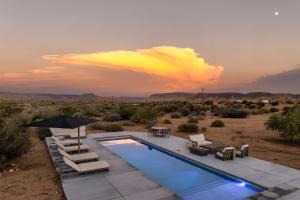 een zwembad in de woestijn met stoelen en een parasol bij La Grange by The CoHost Company in Rimrock