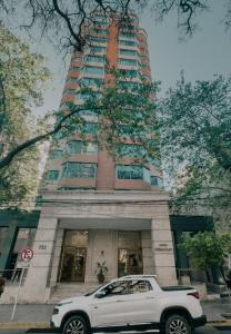 a white truck parked in front of a tall building at Millennium Mendoza pleno Centro 2 dormitorios, cocina completa, pileta y terraza in Mendoza