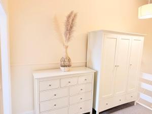een slaapkamer met een witte kast en een vaas op een ladekast bij Modern 4 bedroom property 8 beds wifi smart tv games room pool table in Hull +5 foto's