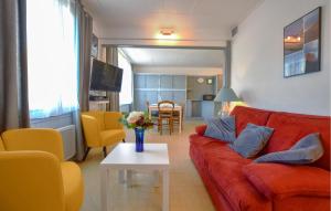 a living room with a red couch and a table at 3 Bedroom Awesome Home In Cabourg in Cabourg