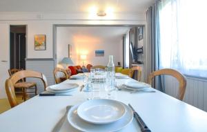 a dining room table with plates and glasses on it at 3 Bedroom Awesome Home In Cabourg in Cabourg
