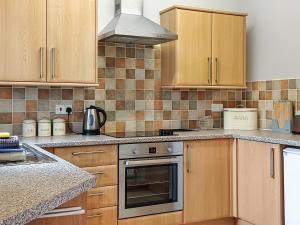 a kitchen with wooden cabinets and a stove top oven at Bwthyn Bwlch in Denbigh