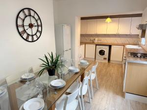 een keuken met een eettafel en een klok aan de muur bij Modern 4 bedroom property 8 beds wifi smart tv games room pool table in Hull
