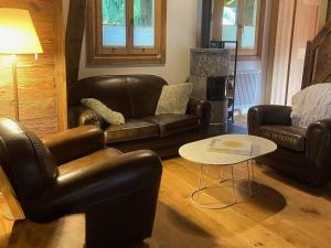 a living room with leather furniture and a table at Chalet Les Ravaires, Morgins in Troistorrents