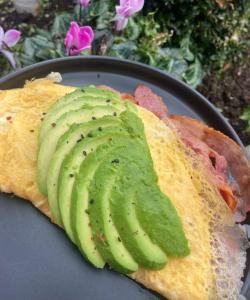 a sandwich with avocado and bacon on a plate at Комната in Wakefield