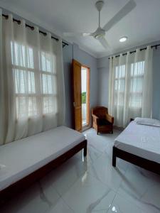 een slaapkamer met twee bedden en een stoel en ramen bij Apartments in Town in Zanzibar City