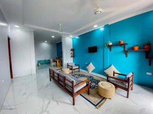 een woonkamer met blauwe muren en een bank en stoelen bij Apartments in Town in Zanzibar City