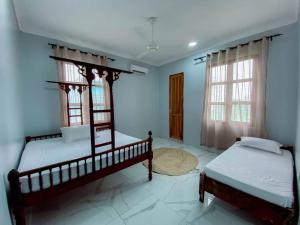twee bedden in een kamer met blauwe muren en ramen bij Apartments in Town in Zanzibar City