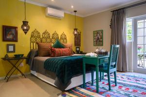 a bedroom with a bed and a table and a desk at Baruch Guesthouse on Lovell in Stellenbosch