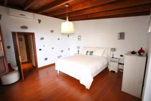 Schlafzimmer mit einem weißen Bett und Holzboden in der Unterkunft Bonita Casa Espectacular Vista in Acojeja