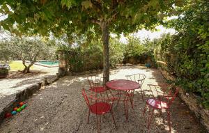 une table et des chaises assises sous un arbre dans l'établissement Maison Avec Piscine Privée, à Lacoste