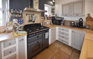 Il comprend une cuisine équipée d'une cuisinière et de placards blancs. dans l'établissement Maison Avec Piscine Privée, à Lacoste