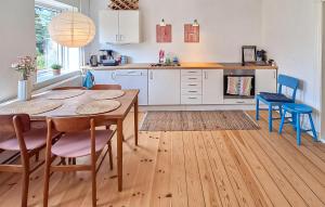 a kitchen with a wooden table and chairs and a kitchen with white cabinets at Beautiful Home In Ærøskøbing in Bro