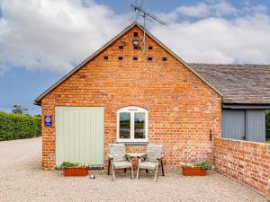 BurltonにあるThe Dairy - Uk10957のレンガ造りの建物で、目の前にテーブルと椅子があります。