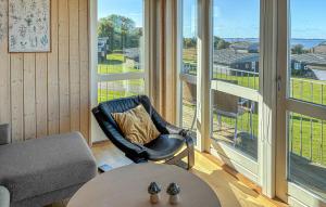Una sala de estar con una silla y una mesa y grandes ventanales. en Amazing Apartment In Faaborg With Sauna, en Nabbe