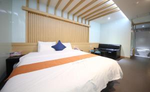 a bedroom with a large white bed with a blue pillow at Nampo MGM Hotel in Busan