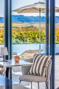 a table and chair with a pillow and an umbrella at Royal Tiki Lodges - Maison d'hôtes avec Piscine chauffée & SPA in Plaissan