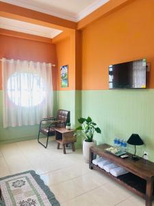 a living room with a couch and a tv on the wall at An Homestay 2 in Phan Thiet