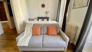 a gray couch with two orange pillows on it at POITTE - Appartement Rennes 10P in Rennes +29 photos