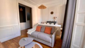 a living room with a couch and two orange pillows at POITTE - Appartement Rennes 10P in Rennes