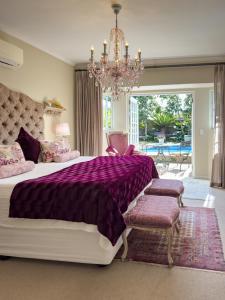 a bedroom with a large bed and a chandelier at Baruch Guesthouse on Lovell in Stellenbosch