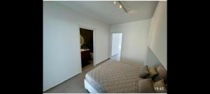 a white bedroom with a bed and a room with a bathroom at Casa Marirò in Marina di Ragusa +5 photos