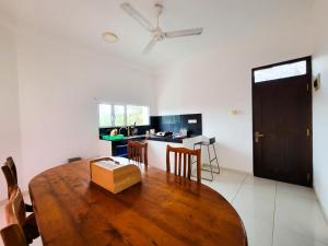 a dining room with a wooden table and a kitchen at Nuwan Inn in Hikkaduwa