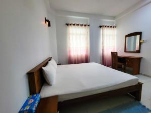 Schlafzimmer mit einem Bett, einem Schreibtisch und einem Spiegel in der Unterkunft Nuwan Inn in Hikkaduwa
