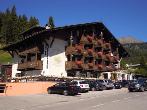 a large building with cars parked in front of it at Hotel Orsingher in San Martino di Castrozza