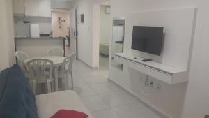 una cocina blanca con mesa y TV. en CONDOMINIO PEROLA DE PORTO, en Porto de Galinhas