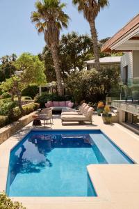 a swimming pool in a yard with palm trees at Nalu Villa in Cape Town