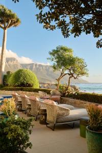 a patio with chairs and tables and the ocean at Nalu Villa in Cape Town