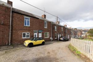a yellow car parked in front of a brick building at 2-Bed House•Free Parking•WiFi•Long Stays Welcome in Ferryhill