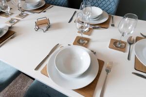 une table blanche avec des assiettes et des verres dessus dans l'établissement Spacious 3BR • WiFi • Parking • Contractor Stay, à Monkwearmouth