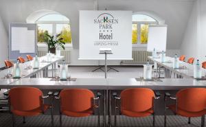 a conference room with a large table and orange chairs at Sachsenpark-Hotel in Leipzig