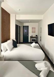 two white beds in a room with a tv at Amsterdam Hotel in London