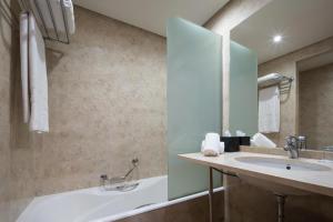 a bathroom with a sink and a tub and a mirror at Eurostars Al-Ándalus Palace in Seville