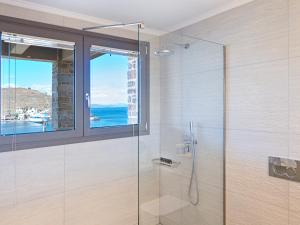 a bathroom with a glass shower with a window at KEOS by the sea in Korissia +197 photos