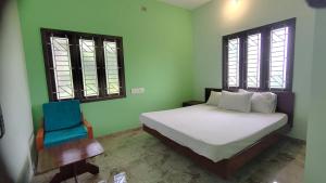 a bedroom with a bed and a blue chair at Aruna homes Thanjavur in Thanjāvūr