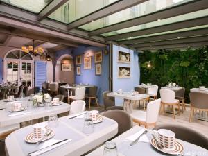 a restaurant with white tables and chairs at Hotel Daumesnil-Vincennes in Vincennes