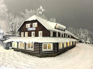ein schneebedecktes Gebäude mit Schnee darüber in der Unterkunft Bílá Labuť Pec in Pec pod Sněžkou + 23 Fotos