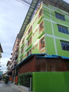 a green building on a street next to a building at Natcha Place Klongluang 35 in Ban Bang Khan