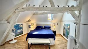a bedroom with a blue bed in an attic at Maison Coup de Cœur in Beaune