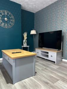 a living room with a tv and a clock on the wall at Luxurious Room in Hackington