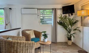 ein Wohnzimmer mit Korbstühlen und einem TV in der Unterkunft Koho SXM - ex Hevea Hotel in Grand Case