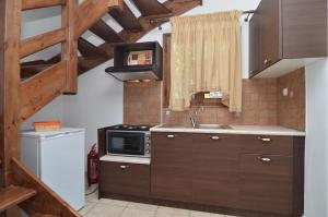 a kitchen with wooden cabinets and a microwave and a sink at Arsinoi Stonehouses in Limenaria