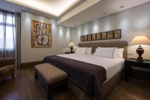 セビリアにあるEurostars Al-Ándalus Palaceの大きなベッドと椅子のあるホテルの部屋