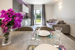 a kitchen and living room with a table with purple flowers at Holiday Apartments Campoverde in Salò
